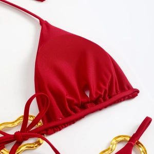Close-up of red bikini top featuring gold heart hardware and gathered fabric detail