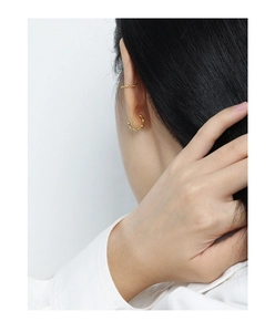 Close-up of minimalist gold twisted hoop earrings and ear cuff on model ear