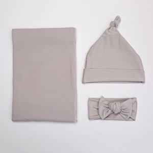 Three-piece newborn swaddle set with matching knot hat and bow headband in light grey