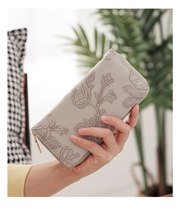Close-up of light grey long wallet featuring textured rose floral embossing and gold zipper