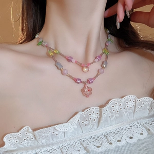 Detail of colorful resin beaded necklace with a pink translucent flower pendant on model