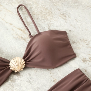 Detail of mocha brown bikini top with gold scallop metal piece on stone background