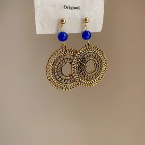 Detailed view of bohemian gold hollow disc earrings with navy blue beads on card
