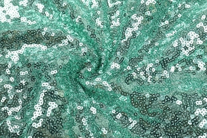 Macro shot of emerald green sequin fabric with dense scale-like pattern and rich texture