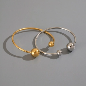 Detail of 18K gold and silver plated stainless steel open bangles with spherical ends