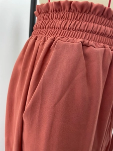 Détail de la taille élastique plissée et de la poche latérale du pantalon large rouge rouille