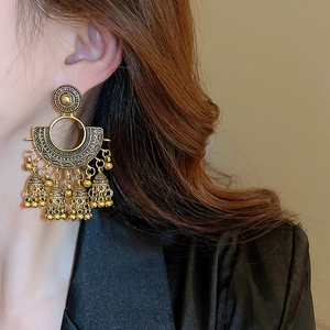 Detailaufnahme von runden goldenen Fächer-Ohrringen mit Quasten an einem Modell
