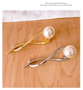 Detailed view of elegant gold and silver metal hair clips with large pearl accents