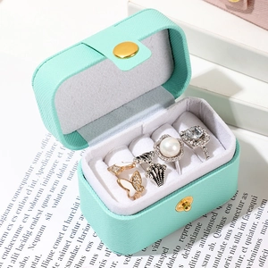 Macro view of mint green travel jewelry box with velvet slots for rings and earrings
