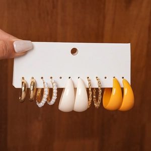 Close-up of 6-pair gold and pearl earring set on display card over wooden texture