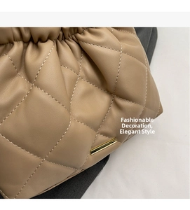 Detail of beige quilted cloud bag showing faux leather texture and gold metal accents