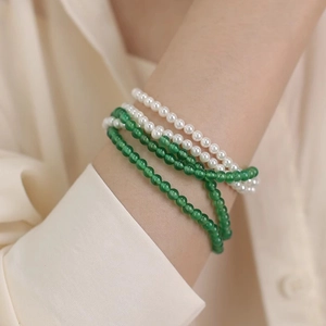 Close-up of layered necklace with white faux pearls and green agate style beads