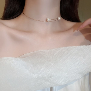 Close-up of minimalist gold chain necklace with double pearls on model's collarbone
