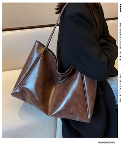 Gros plan d'un cabas marron vintage montrant le similicuir brillant et les anses minimalistes