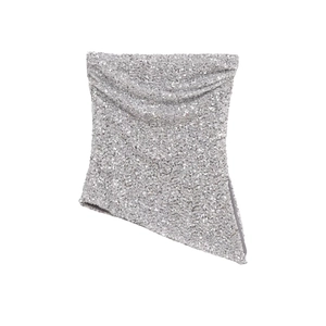 Dettaglio del top a fascia con paillettes argento con orlo asimmetrico e tessuto lucido