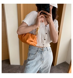 Mirror selfie showing the vibrant orange cloud bag with a chunky gold chain strap detail