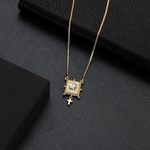 Close-up of gold plated square pendant with heart-shaped zircon and small cross detail