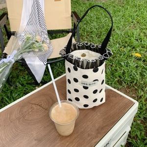 Close-up of polka dot canvas bucket bag with lace trim in a picnic setting