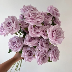 Close-up of artificial light purple silk roses bouquet held in hand for wedding decor