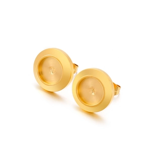 Close-up of golden round metal stud earrings with brushed texture and recessed groove