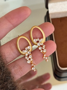 Vue détaillée des boucles d'oreilles ovales dorées avec pompons en cristal clair