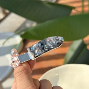 Close-up of marble acetate hair clip with colorful rhinestones on a metal duckbill base