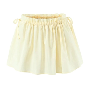 Detail of pale yellow mini skirt featuring ruffled waist and adjustable side drawstrings