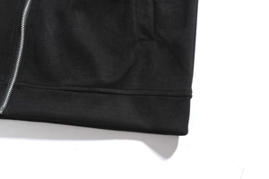 Detailed view of black jacket with metallic zipper, side pocket and elastic hem detail
