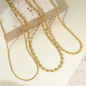 Minimalist gold oval bead chain necklaces in thick and thin styles on stone background