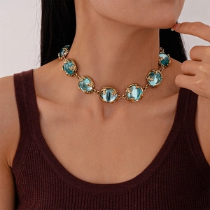 Detail view of vintage light blue resin circular gems on a gold chain necklace