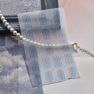 Detail of French A1 style nail stickers with blue stripes on elegant pearl background