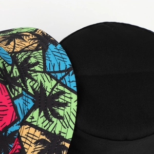 Detail of vibrant tropical palm tree print and solid black reversible cotton bucket hat