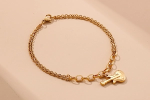Detailed view of a gold double-layer chain bracelet featuring a guitar shaped pendant