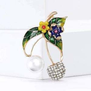 Detail of cherry brooch with white pearl, green enamel leaves and sparkling rhinestones