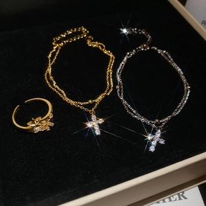 Close-up of gold ring and layered cross necklaces with zircon on black velvet