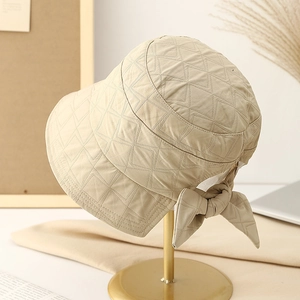 Women's quilted plaid bucket hat with rear bow detail on elegant gold display stand