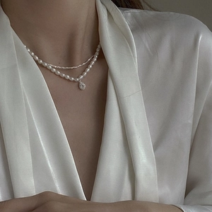 Detail of layered freshwater pearl necklace with sparkling teardrop zircon pendant on neck