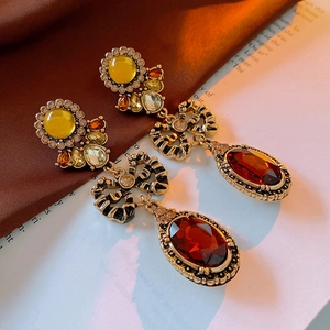 Detail of vintage palace style gold earrings with red oval gemstone and bow tie accent