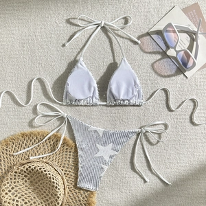 Flat lay of white bikini set with silver star sequins and summer vacation props