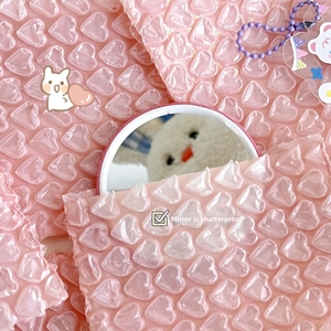 Close-up of pink heart bubble wrap protecting a round mirror against impact and scratches