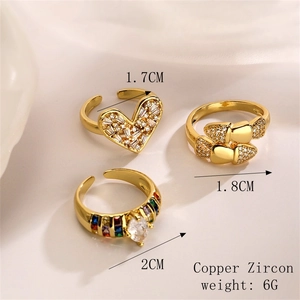 Detailed view of three gold-plated copper rings with colorful zircons and size labels