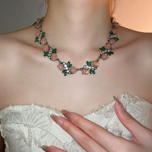 Detailed close-up of a vintage resin necklace with pink beads and green leaf accents