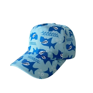 Detail of light blue kids baseball cap featuring blue and white cartoon shark patterns