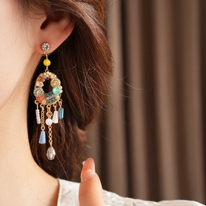 Détail de boucles d'oreilles bohèmes avec pampilles colorées et cristaux sur mannequin