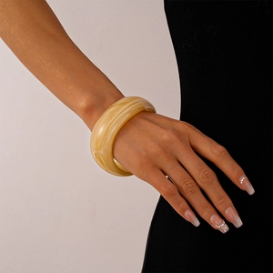Detail of an amber acrylic wide cuff bracelet with vintage marbled texture on a model arm