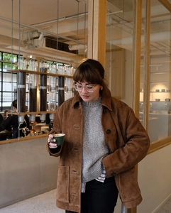 Détail d'une veste vintage en daim marron avec de gros boutons et un col à revers