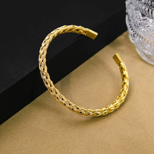 Detailed view of a gold woven cuff bracelet with intricate twisted metallic textures