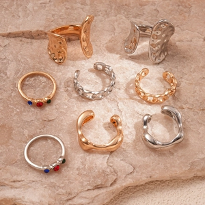 Five-piece geometric gold and silver ring set with colored rhinestones on rock surface
