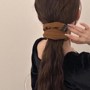 Brown knitted scrunchie with textured fabric on model hair featuring a small woven label