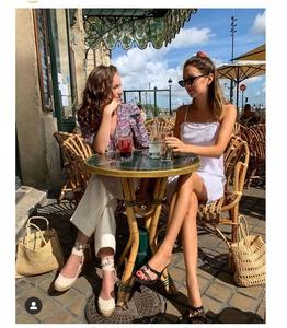 Chic straw tote bag placed on sidewalk in stylish outdoor summer cafe setting